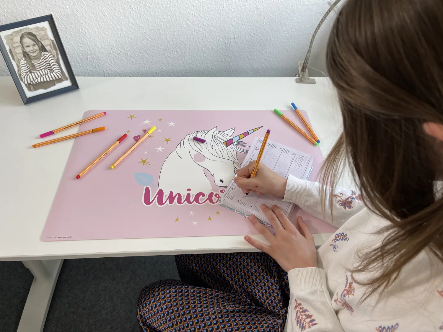 Schreibtischunterlagen, ein Mädchen schreibt Tagebuch auf einer Einhorn-Schreibtischunterlage